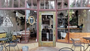 Un café con fachada rústica, ventanas amplias y terraza.