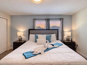 A hotel room with a large bed, two bedside tables with lamps, a window with curtains, and a view of the cityscape.