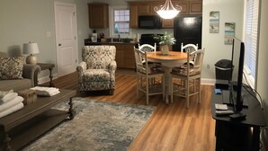 A living room with a sofa, armchair, and coffee table, a dining area with a table and chairs, a kitchen with cabinets and appliances, and a ceiling fan. - 2 BR, 1 bath w full kitchen on ground level w full kitchen w access to amenities (Murrells Inlet)