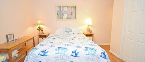 A bedroom with a bed, two bedside tables, a ceiling fan, and a door.