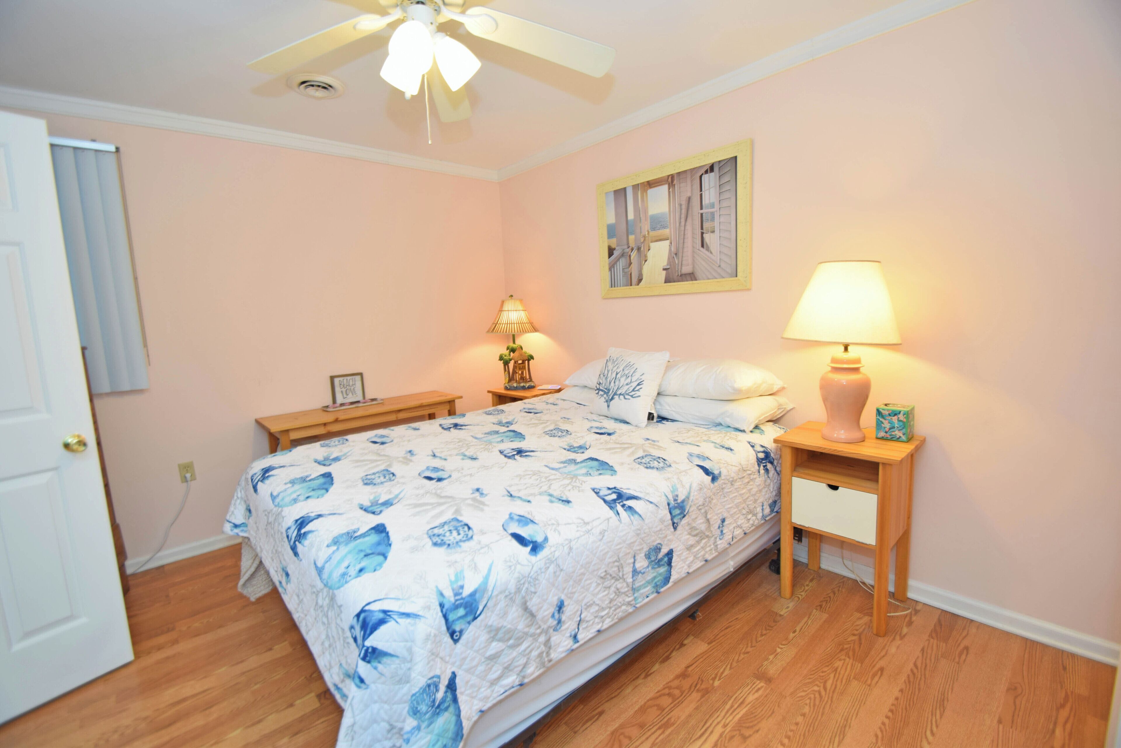 Un dormitorio con cama, mesitas de noche, lámpara y ventilador de techo.