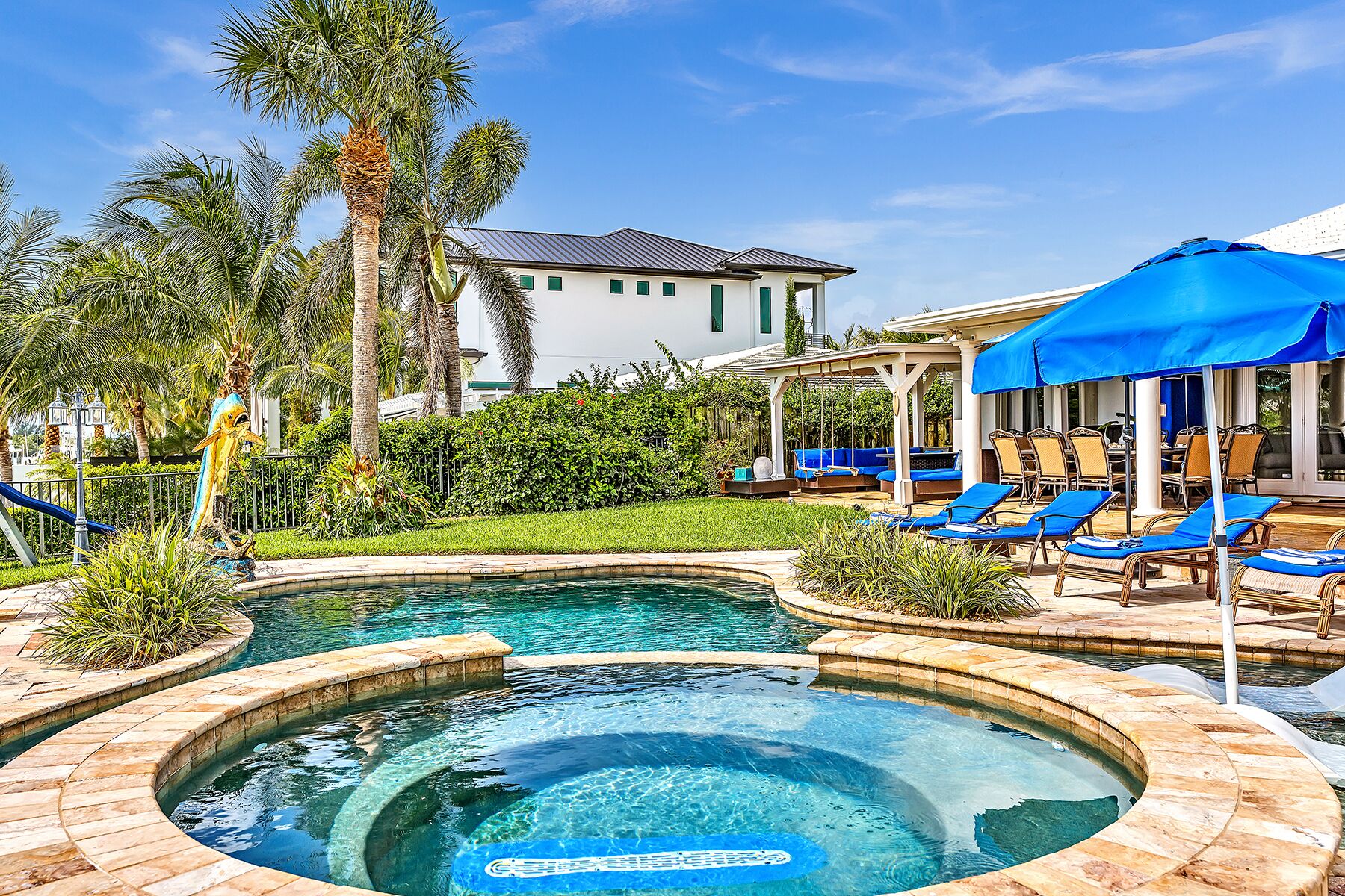 Une piscine avec un jacuzzi, des chaises longues et des parasols.