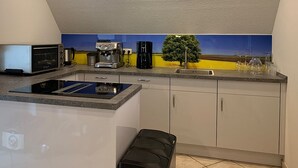 Una cucina con piano cottura integrato, macchina per il caffè e vista sul paesaggio attraverso una finestra.