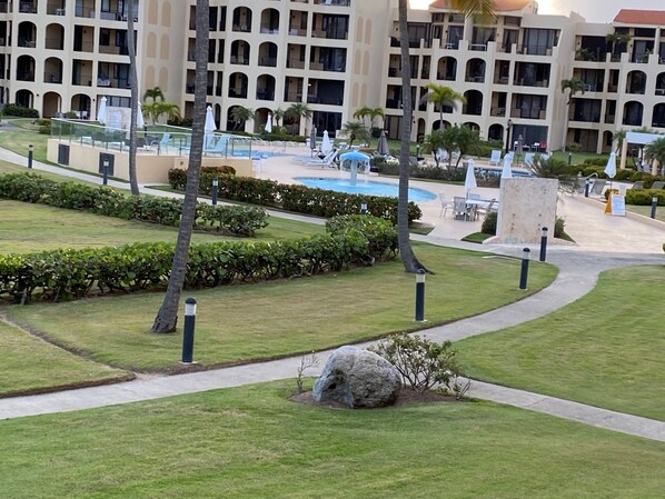 A hotel with a swimming pool, palm trees, and a well-maintained lawn. - Amazing Ocean View 2 bedroom 2 Bath Villa In Pal Mas Del Mar Resort (Humacao)