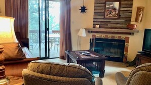 Ein Wohnzimmer mit Kamin, Fernseher und Essbereich mit Tisch und Stühlen.