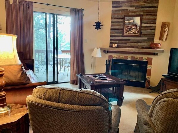 A living room with a fireplace, a television, and a dining area with a table and chairs.