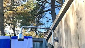 A wooden outdoor shower with a blue and white striped towel, two bottles of Dove body wash, and a handheld showerhead. - BEST OF ALL WORLDS! Beach, Lake, Town, Bike, and Comfort. (Chatham)