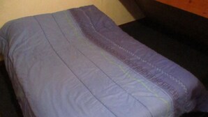 Una cama con una manta azul y una almohada.