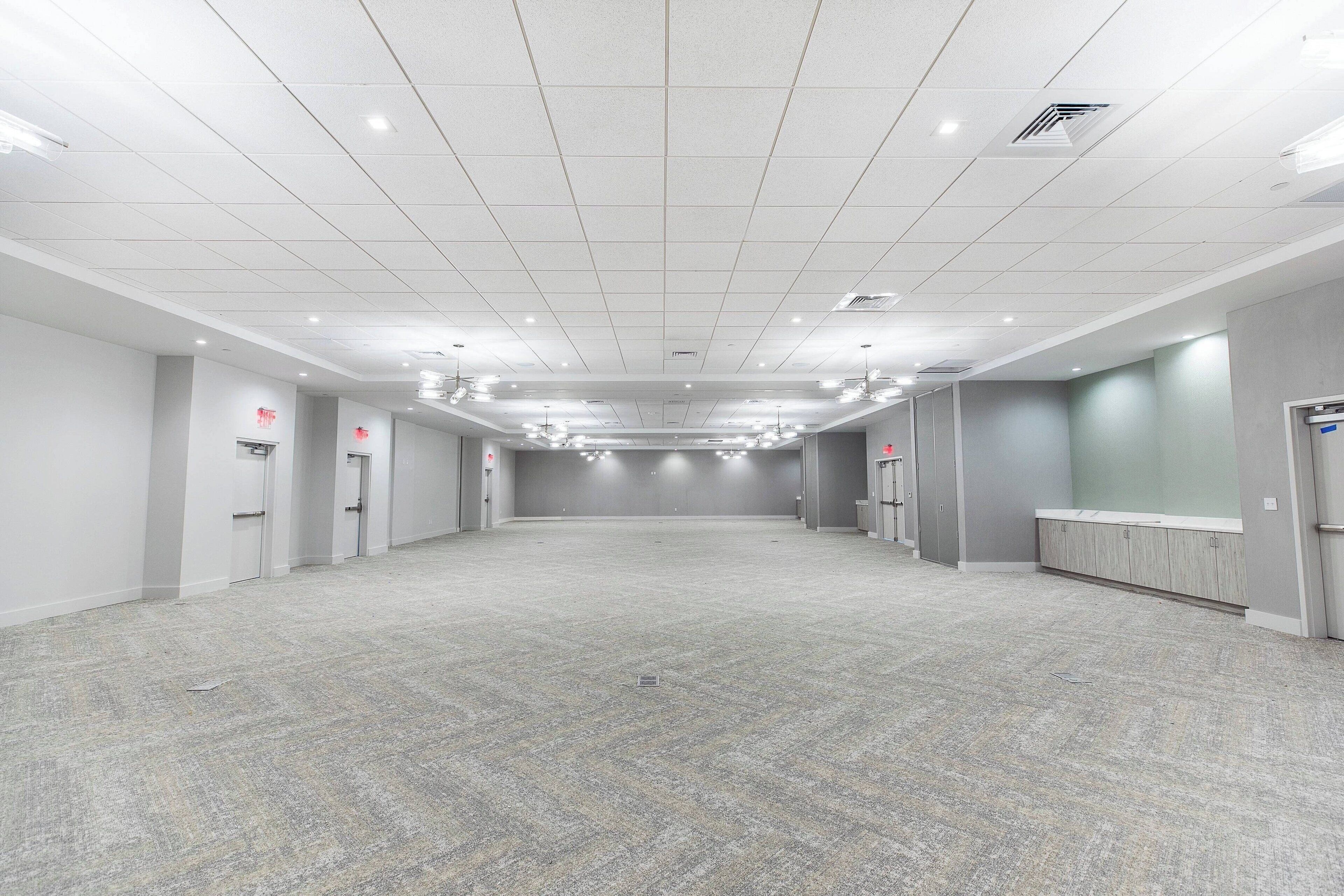 A spacious, well-lit hotel lobby with a tiled ceiling, multiple doors, and a reception desk.