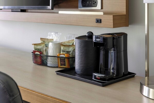 Una cafetera y un cesto con cápsulas de café sobre una encimera.