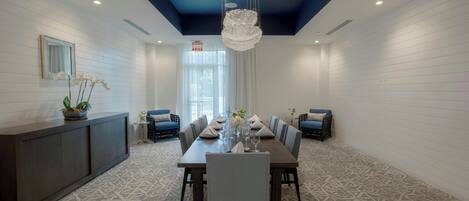 A modern dining area with a long table set for six, surrounded by chairs.