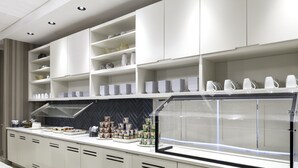 Een moderne keuken met witte kasten, een inbouwoven en een glazen vitrine.