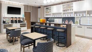 A modern cafe with a bar area, seating, and a TV mounted on the wall.