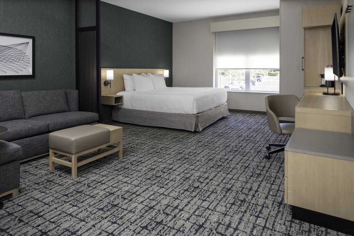 Una habitación de hotel con cama, sofá, escritorio y televisión.
