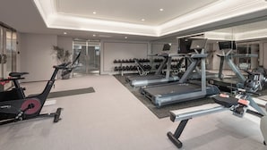 Ein modernes Fitnessstudio mit Trainingsgeräten, Laufbändern und einer Wand voller Kurzhanteln.