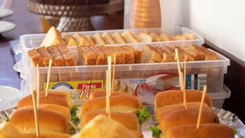 A buffet table with various food items including sandwiches, bread, and a juice dispenser.