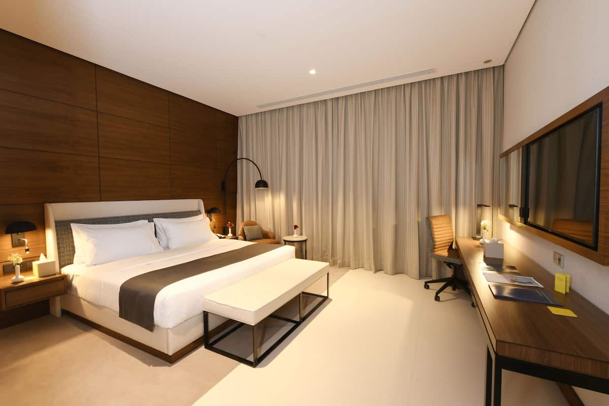 A hotel room with a large bed, bedside tables, a desk, and a chair.