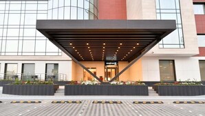 A modern hotel entrance with a covered walkway, large windows, and a well-maintained outdoor area with planters. - Golden Tulip Riyadh (Riyadh)