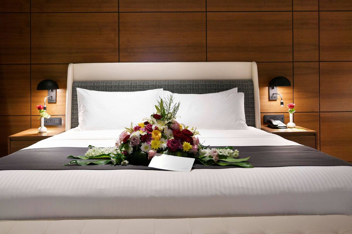 A hotel room with a large bed, two bedside tables, and a wooden wall paneling.