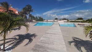 Ein Poolbereich mit zwei Pools, einem gepflasterten Weg und Palmen.