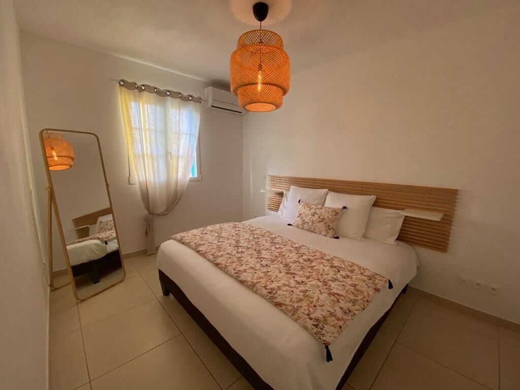 A bedroom with a bed, a mirror, and a hanging light fixture.