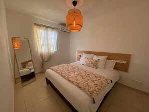 A bedroom with a bed, a mirror, and a hanging light fixture. - Orient Bay Beach Front Apartment (Collectivity of Saint Martin)