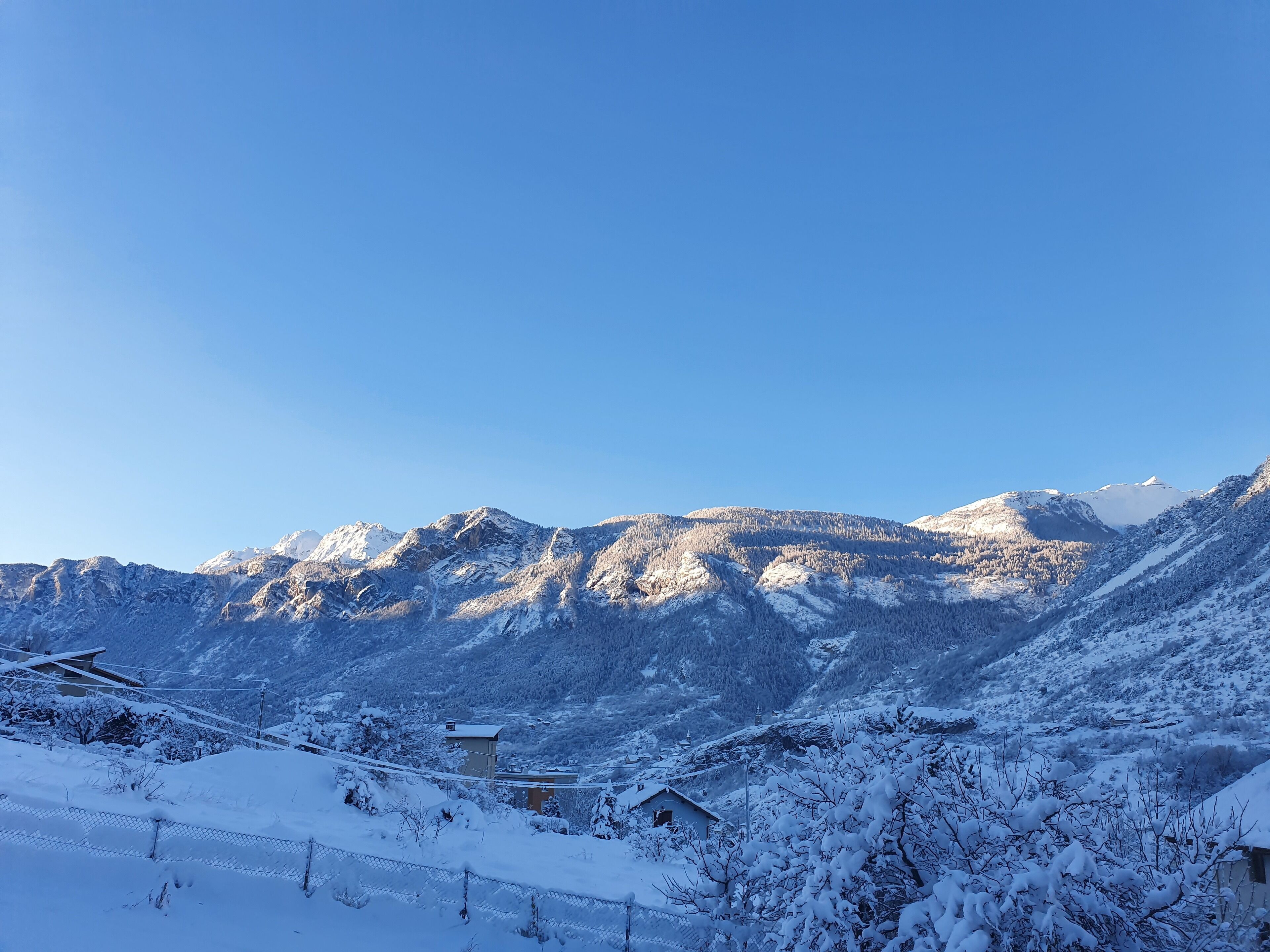 Paisaje montañoso nevado con un pequeño edificio en primer plano.