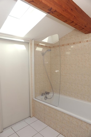 Een douche met glazen wanden, een badkuip en een betegelde vloer.