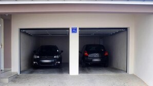 Een parkeergarage met twee geparkeerde auto's, een blauw bord boven de ingang en een betonnen vloer.