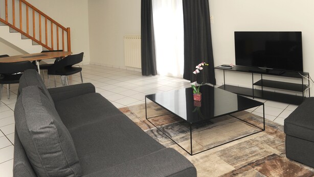 Een moderne woonkamer met een bank, salontafel, televisie en een trap.
