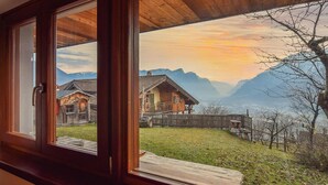 A wooden-framed window with a view of a mountain landscape, including houses and a wooden fence. - Cozy home in Telve di Sopra (Telve di Sopra)