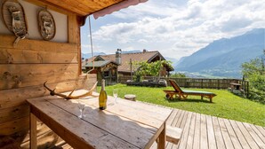 A wooden deck with a table and chairs, a bottle of wine, and a view of a mountain landscape. - Cozy home in Telve di Sopra (Telve di Sopra)