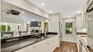 Una cocina moderna con armarios blancos, encimera negra y estufa integrada.