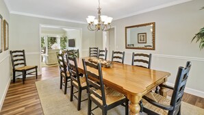 Un comedor con una mesa y sillas de madera, una araña y un espejo en la pared.