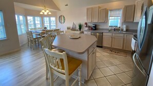A spacious kitchen with a central island, wooden chairs, a dining table, and a view of the dining area. - 2 min walk to boardwalk, beach or town from this 2nd floor 4br 2ba gem! (Ocean City)