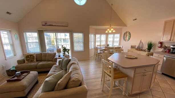 A spacious living area with a large sofa set, a dining table, and a kitchen area with a central island. - 2 min walk to boardwalk, beach or town from this 2nd floor 4br 2ba gem! (Ocean City)