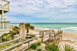 A beach with wooden walkways, a lifeguard tower, and a clear view of the ocean.