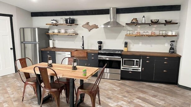 A modern kitchen with a central island, built-in appliances, and wooden cabinetry.