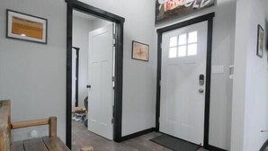 A hallway with wooden benches, white doors, and a sign above one door.