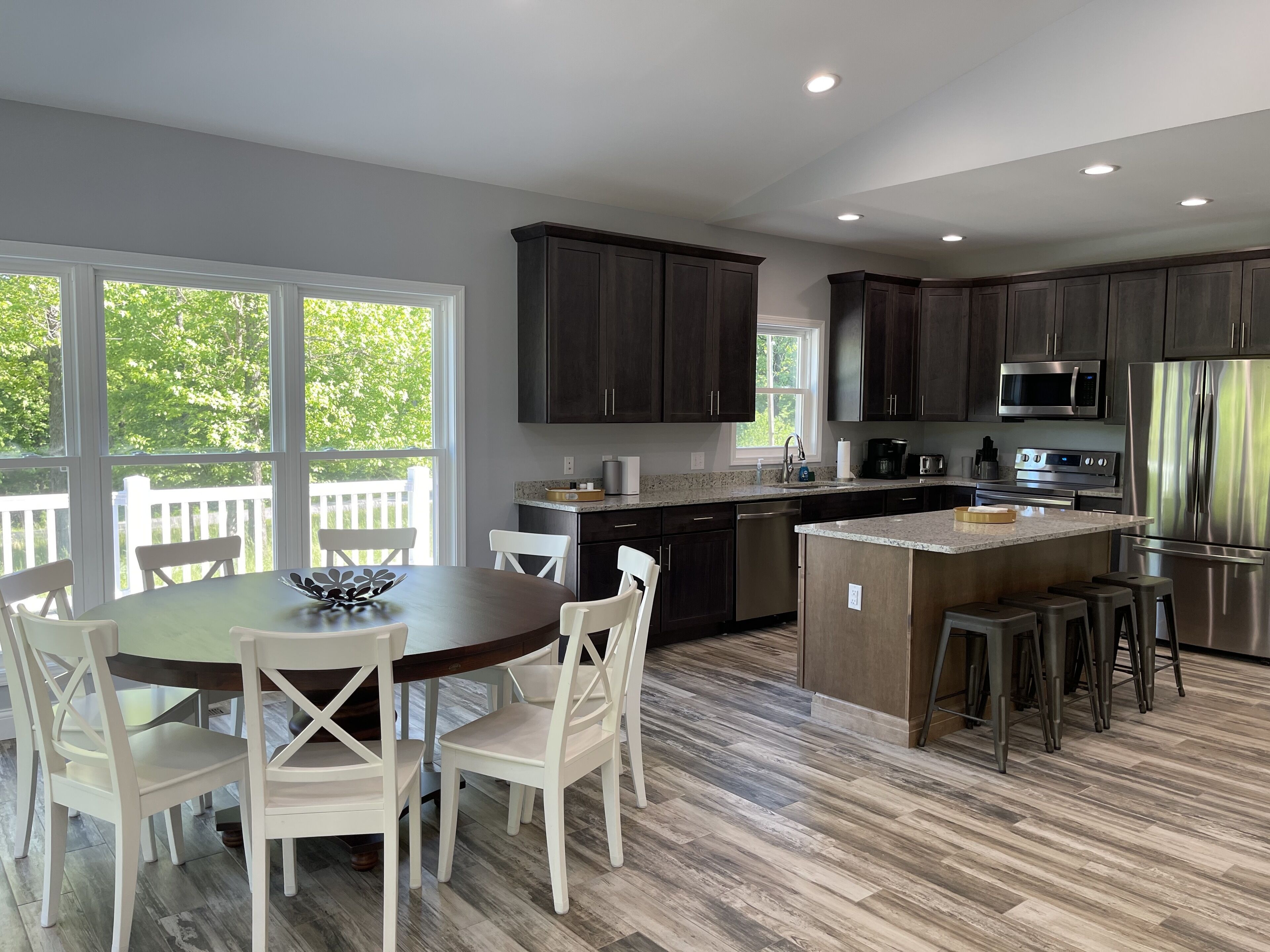 A modern kitchen with dark wood cabinets, stainless steel appliances, and a large island with stools.