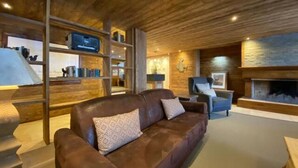 A cozy living room with a leather sofa, a fireplace, and wooden shelves.
