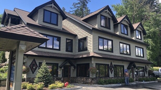 A two-story building with a stone foundation, multiple windows, and a covered front porch. - Lake view , Cozy One Bedroom! Walk to Beach and Town! (Bolton)