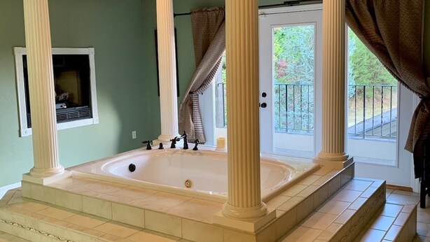 A spa area with a large freestanding bathtub, a fireplace, and a balcony with a railing. - Splash in the Smokys ! (Sevierville)