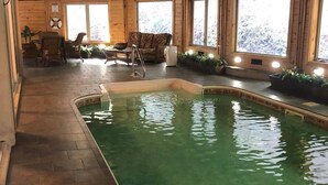 A swimming pool with a wooden ceiling and a view of the outdoors through large windows. - Splash in the Smokys ! (Sevierville)