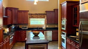 A spacious kitchen with dark wood cabinets, a central island, and a large window providing natural light. - Splash in the Smokys ! (Sevierville)