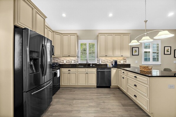 A modern kitchen with beige cabinetry, a black refrigerator, and a central island.