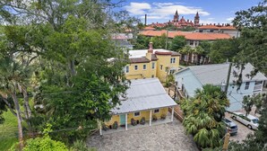 A courtyard with a building featuring a tiled roof and a porch with chairs. - Citrus Hideaway l Hot Tub l 1 Block to Downtown (St. Augustine)