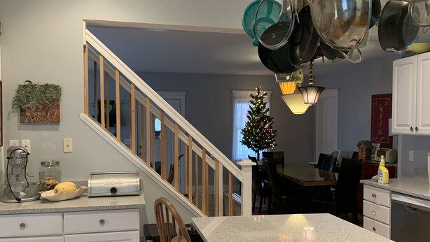 Eine Küche mit einer großen Kochinsel, Holzküchenstühlen, einer Treppe und einem Weihnachtsbaum.