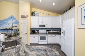 A kitchen with white cabinets, a microwave, a stove, and a refrigerator.