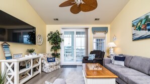 A living room with a sofa, coffee table, TV, and a plant.